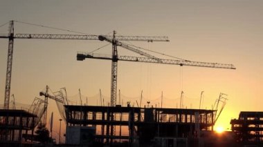 Seville, İspanya-03 Ocak 2019: 4K, inşaat ve sanayi kulesi vinçleri olan gün batımı. Şafak sökücü vinç şehirde bir evde çalışıyor. Sarı güneş ışığı olan yeni bina Dan.