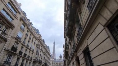 4K, Paris, Fransa 'da kış günü eski evleri olan bir sokaktan Eyfel Kulesi Manzarası. Avrupa 'nın ünlü turistik yerlerinde bulutlu bir gökyüzü. Eiffel turuyla yağmurlu bir gün. Arka plan Dan.