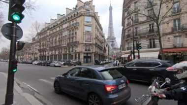 Paris, Fransa-13 Ocak 2018-4K, Paris, Fransa 'da kış günü eski evleri ve trafiği olan bir sokaktan Eyfel Kulesi manzarası. Avrupa 'nın ünlü turistik yerlerinde bulutlu bir gökyüzü. Yağmurlu gün - Dan