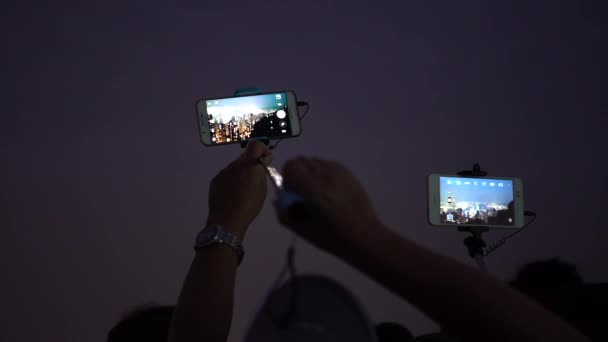 4Kアジア観光客有名な展望台から香港島のスカイラインの空中写真を撮るためにスマートフォンを使用している人々タワービクトリアピークダン — ストック動画