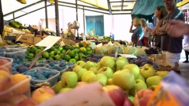 Venedik, İtalya-20 Eylül 2018: 4K Satış elemanı geleneksel Rialto pazarında elma ve çeşitli sebzeler satıyor. İtalyan satıcılar sokak tezgahında gıda malzemeleri satıyorlar. Meyveli haplar.