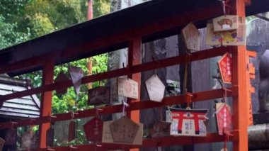 Kyoto, Japonya-14 Nisan 2019: Fushimi Inari Taisha tapınağının ünlü topraklarındaki küçük bir tapınakta Japon tılsımlarının Yavaş Hareketi. İnsanlar kendilerini kötü şeylerden korumak için muskaya inanırlar.