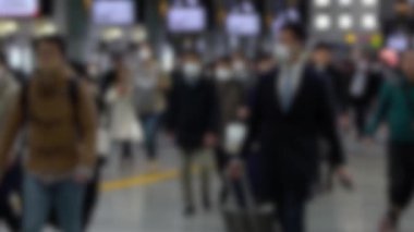 Yavaş çekim bulanık Japon yolcuları Coronavirus enfeksiyonunu önlemek için Shinagawa İstasyonu 'nda maske takıyor. Virüs acil duruma neden oldu.