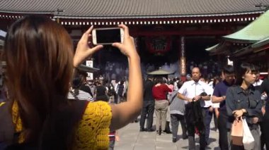 Tokyo, Japonya-01 Ekim 2017: 4K Asyalı kadın Asakusa 'daki ünlü Budist tapınağı Senso-ji' nin akıllı telefonuyla fotoğraf çekti. Turistler Tokyo 'daki Sensoji tapınağını ziyaret eder ve Japon shinto tapınağını resmederler. Japonya - Dan