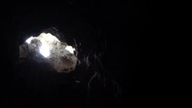 Malezya 'daki güzel doğal kireçtaşı mağarasında güneş ışınlarıyla uçan yarasa avı. Küçük yarasalar, Batu mağaralarının tepesinde bulunan Karanlık Mağara 'daki deliğin içinden güneşli ışık huzmeleriyle uçarlar.