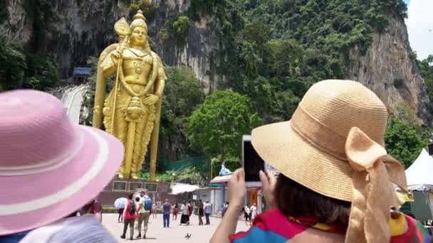 马来西亚吉隆坡 2018年4月13日 4K亚洲女人在马来西亚巴图洞穴入口与著名的穆鲁甘勋爵雕像的智能手机合影 游客们参观并描绘了一座印度教寺 — 图库视频影像