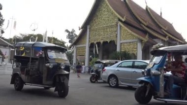 Chiang Mai, Tayland-08 Nisan 2016: Wat Ho Tham 'ın kapısında Tuk-tuk ile turistlerin 4K turu. Wat Chedi Luang 'daki Wat Sukmin, Chiang Mai-Dan' in tarihi merkezinde bir Budist tapınağıdır.