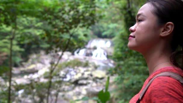 4Kアジアの女性ハイカーは山の中で川と小さな滝を見ています バックパッカーの女の子の森の中で万葉のカスケード近くの木々の間を歩くと 国立レクリエーションエリア新兵衛台湾ダン — ストック動画
