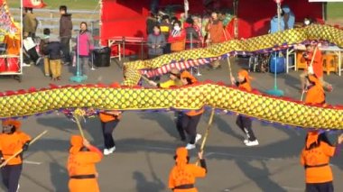 Miaoli, Tayvan-11 Şubat 2017: Tayvan Festivallerinde Hakka Ejderha Bombalama Dansı Ağır çekim kadın takımı. Bir çok insan ejderhayı bir aşağı bir yukarı hareket ettiriyor, seyirciler plazaya bakıyor.