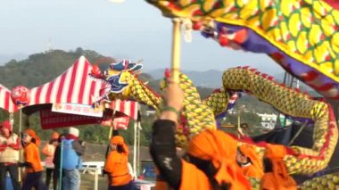 Miaoli, Tayvan-11 Şubat 2017: Tayvan Festivallerinde Hakka Ejderha Bombalama Dansı Ağır çekim kadın takımı. Bir çok insan ejderhayı bir aşağı bir yukarı hareket ettiriyor, seyirciler plazaya bakıyor.