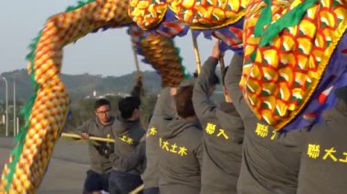 Miaoli, Tayvan-11 Şubat 2017: Hakka Ejderha Bombalama Dansı Tayvan 'da Ağır çekim Festivali. Bir kaç kişi ejderhayı yukarı aşağı hareket ettiriyor ve yan yana, seyirciler şehir meydanına bakıyor-Dan