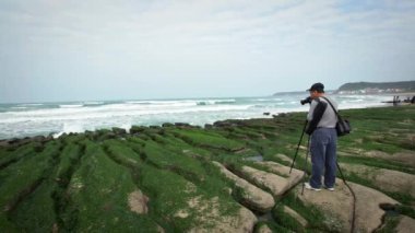 Laomei, Tayvan-27 Şubat 2018: 4K Asyalı Fotoğrafçı ünlü Laomei Green Reef New Taipei şehrinin DSLR kamerasıyla fotoğraf çekiyor. Turistler, kıyı şeridinde kırılan deniz dalgalarını ziyaret edip fotoğraf çekiyorlar