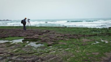 Laomei, Tayvan-27 Şubat 2018: 4K Asyalı Fotoğrafçı ünlü Laomei Green Reef New Taipei şehrinin DSLR kamerasıyla fotoğraf çekiyor. Turistler, kıyı şeridinde kırılan deniz dalgalarını ziyaret edip fotoğraf çekiyorlar