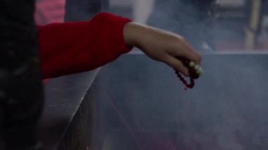 Nankunshen Daitian Tapınağı 'nda dua eden Asyalılar. Tapanlar bir kolye tutarken, dumanla kutsandılar. Çin 'in yeni yılındaki Taocu tapınağı. Dini ritüeller gerçekleştiriliyor - Dan