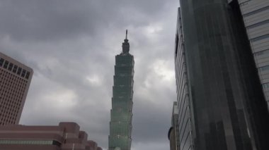Taipei, Tayvan 18 Mayıs 2015: 4k Taipei 101 Kulesi. Tayvan 'da karanlık bir gün arabalarla, motosikletlerle ve Xinyi İlçesi-Dan' de çok yüksek gökdelenli yollarla şehir manzarası yağıyor.