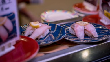 Japonya 'da bir restoranda taşıma bandında suşi. Geleneksel Kaitenzushi Japon yemekleri. Shushi Go Round, Asya 'da suşi treni olarak da bilinen ünlü bir fast food türüdür..
