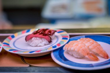 Japonya 'da bir restoranda taşıma bandında suşi. Geleneksel Kaitenzushi Japon yemekleri. Shushi Go Round, Asya 'da suşi treni olarak da bilinen ünlü bir fast food türüdür..