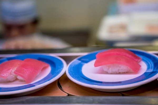 Sushi on conveyor belt in a Japan restaurant. Traditional Kaitenzushi Japanese food. Shushi Go Round is a famous form of fast food in Asia, also known as sushi train.