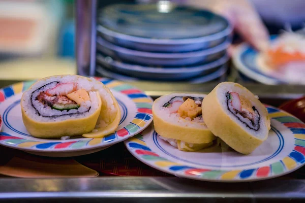 Sushi on conveyor belt in a Japan restaurant. Traditional Kaitenzushi Japanese food. Shushi Go Round is a famous form of fast food in Asia, also known as sushi train.