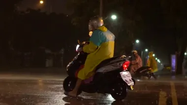 Taipei, Tayvan-29 Temmuz 2017: Taipei 'de gece yağmur yağarken ağır çekimde yağmurluk giyen insanlar motosiklet kullanıyor. Tayvan-Dan 'de Asya caddesinde yağmur yağıyor