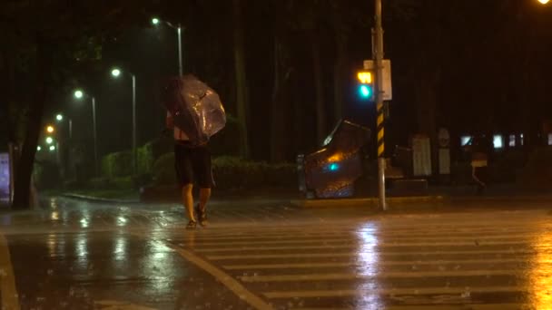 スローモーション台北市の台風ネサットの間に通りを横断するのに苦労して傘を持つ歩行者の男性 極端な風と雨の夜 ダンの強いハリケーン風 — ストック動画