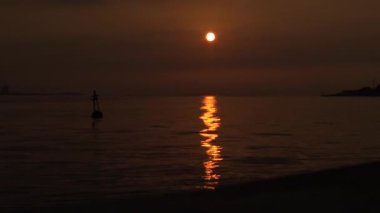 Sahile yakın yüzen bir şamandıra güneş yavaşça dalgalanan okyanus yüzeyinde parıldıyor, güneş ışığı okyanusun sakin sularına yansıyor. Tamshui 'nin Günbatımı, Tayvan-Dan