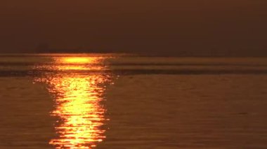 Güneş hafifçe dalgalanan okyanus yüzeyinde parıldıyor, güneş ışığı okyanusun sakin suyuna yansıyor 4k. Tamshui 'nin Günbatımı, Tayvan-Dan