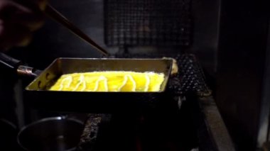 Tokyo şehir merkezindeki bir markette metal tavalarda Tamagoyaki omletlerinin Yavaş Hareketi. İzakaya restoranında popüler Japon sokak yemekleri.