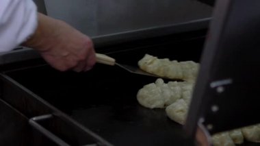Yavaş çekimde tavada kızartılmış guotie. Profesyonel bir aşçı, ızgarada kızartılmış hamur köftesi pişiriyor. Japon lezzetli yemekleri. Adam bir restoranda yemek pişiriyor, geleneksel bir mutfakta çalışıyor.