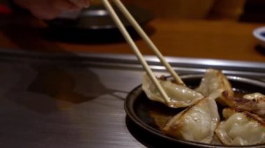 Lokantada kızarmış hamur köftesini soya sosuna yavaş yavaş batırmak. Servis edilen sıcak geleneksel Japon yemeklerini ye. Gyoza 'nın küçük lokma porsiyonları olarak hazırlandı.