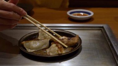 Lokantada kızarmış hamur tatlısı yemek için yemek çubuklarını yavaş çekimde kullanmak. Guotie geleneksel bir Japon yemeğidir. Lezzetli Gyoza porsiyonları masada servis ediliyor Dan.