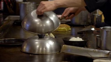 Yavaş çekimde tavada kızartılmış guotie. Profesyonel bir aşçı, ızgarada kızartılmış hamur köftesi pişiriyor. Japon lezzetli yemekleri. Adam bir restoranda yemek pişiriyor, geleneksel bir mutfakta çalışıyor.