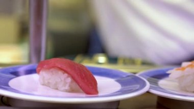 Japonya 'daki bir restoranda hareket halindeki taşıyıcı bantta yavaş suşi hareketi. Geleneksel Kaitenzushi Japon yemekleri. Shushi Go Round Asya 'da yaygın bir fast food çeşididir, suşi treni olarak da bilinir.