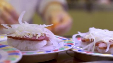 Japonya 'daki bir restoranda hareket halindeki taşıyıcı bantta yavaş suşi hareketi. Geleneksel Kaitenzushi Japon yemekleri. Shushi Go Round Asya 'da yaygın bir fast food çeşididir, suşi treni olarak da bilinir.
