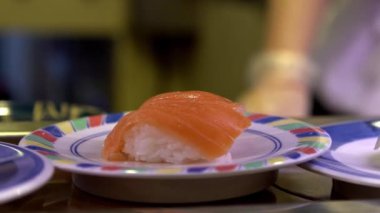 Japonya 'daki bir restoranda hareket halindeki taşıyıcı bantta yavaş suşi hareketi. Geleneksel Kaitenzushi Japon yemekleri. Shushi Go Round Asya 'da yaygın bir fast food çeşididir, suşi treni olarak da bilinir.