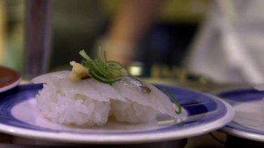 Japonya 'daki bir restoranda hareket halindeki taşıyıcı bantta yavaş suşi hareketi. Geleneksel Kaitenzushi Japon yemekleri. Shushi Go Round Asya 'da yaygın bir fast food çeşididir, suşi treni olarak da bilinir.