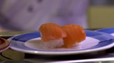 Japonya 'daki bir restoranda hareket halindeki taşıyıcı bantta yavaş suşi hareketi. Geleneksel Kaitenzushi Japon yemekleri. Shushi Go Round Asya 'da yaygın bir fast food çeşididir, suşi treni olarak da bilinir.