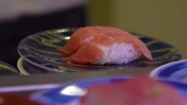 Japonya 'daki bir restoranda hareket halindeki taşıyıcı bantta yavaş suşi hareketi. Geleneksel Kaitenzushi Japon yemekleri. Shushi Go Round Asya 'da yaygın bir fast food çeşididir, suşi treni olarak da bilinir.