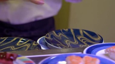 Japonya 'daki bir restoranda hareket halindeki taşıyıcı bantta yavaş suşi hareketi. Geleneksel Kaitenzushi Japon yemekleri. Shushi Go Round Asya 'da yaygın bir fast food çeşididir, suşi treni olarak da bilinir.