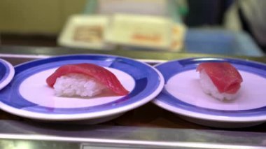 Japonya 'daki bir restoranda hareket halindeki taşıyıcı bantta yavaş suşi hareketi. Geleneksel Kaitenzushi Japon yemekleri. Shushi Go Round Asya 'da yaygın bir fast food çeşididir, suşi treni olarak da bilinir.