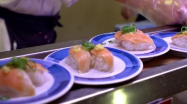Japonya 'daki bir restoranda hareket halindeki taşıyıcı bantta yavaş suşi hareketi. Geleneksel Kaitenzushi Japon yemekleri. Shushi Go Round Asya 'da yaygın bir fast food çeşididir, suşi treni olarak da bilinir.