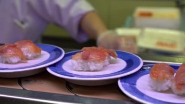 Japonya 'daki bir restoranda hareket halindeki taşıyıcı bantta yavaş suşi hareketi. Geleneksel Kaitenzushi Japon yemekleri. Shushi Go Round Asya 'da yaygın bir fast food çeşididir, suşi treni olarak da bilinir.