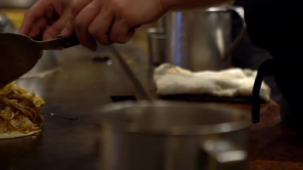 アジア料理店のへら料理とシェフの手のスローモーション詳細 日本のお好み焼きの仕事の準備でプロの料理人として男 — ストック動画