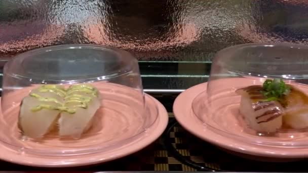日本のレストランで回転コンベアベルトで寿司のスローモーション 伝統的な懐石料理 寿司のゴーラウンドは 寿司列車としても知られているアジアで一般的なファーストフードの有名な形態です — ストック動画
