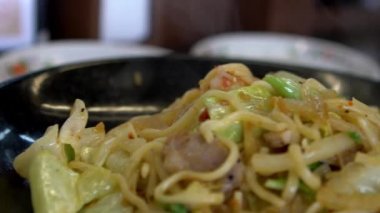 Ağır çekimde Yakisoba Ramen ile domuz eti ve pişmiş yumurta yenmeye hazır. Sebzeli ve etli Asya yemeği Japon makarnası. Kızarmış baharatlı şehriye.