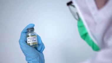 4K, koruyucu giysi giymiş koruyucu bir erkek, aşı şişesi koronavirüsü, Aşı kovid-19 enjeksiyon hastalığı olan beyaz bir adam. Önleme bağışıklığı hastalığı - Dan