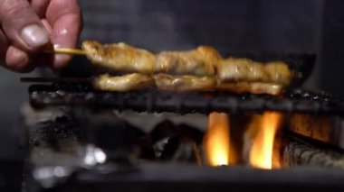 Slow Motion satıcısı Asya 'nın gece pazarında ızgarada domuz şişi pişiriyor. İnsanlar popüler et ızgara barbekü pişirdi. Kömürün alevi. Ünlü bir pazar yeri. Lezzetli Japon yemeği Dan.