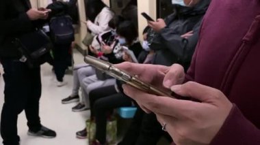 4K, metrodaki Asyalı turist kadın akıllı telefon tutuyor. Yolcu seyahat için metrodaki teknoloji telefonunu kullanıyor. Bir iletişim aracı, modaya uygun bir alet. Yaşam tarzı ve ulaşım - Dan