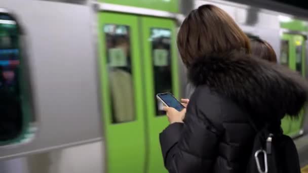 日本东京 2020年4月4日 亚洲年轻女子在日本的一个板式火车站检查她的手机 使用社交网络编写短信 旅客生活方式及交通 — 图库视频影像