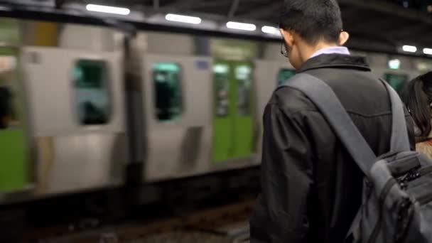東京2020年4月4日 4Kアジアの女性が地下鉄でスマホを使っている ソーシャルネットワークをチェックし 電話デバイス上で行われたテキストを書き込みます 日本の鉄道駅 Danで技術電話を使用する乗客 — ストック動画
